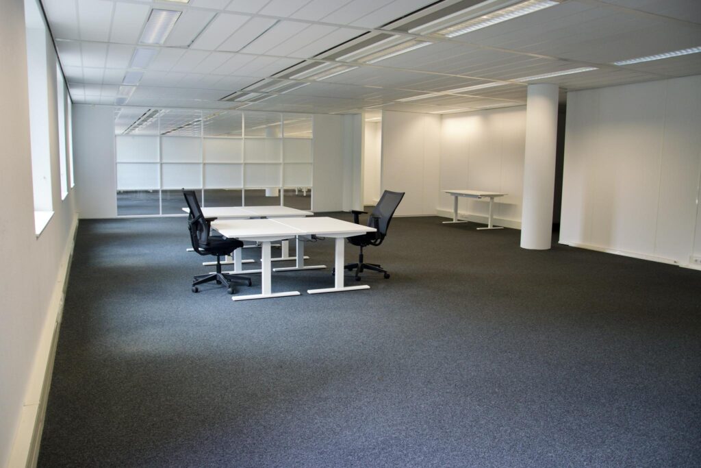 Modern, unfurnished office space with desks and chairs at Koningin Wilhelminaplein.